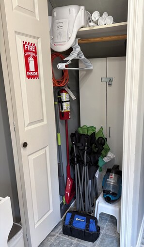 Ein Abstellraum mit Feuerlöscher, Reinigungsmitteln und einem Hochstuhl.
