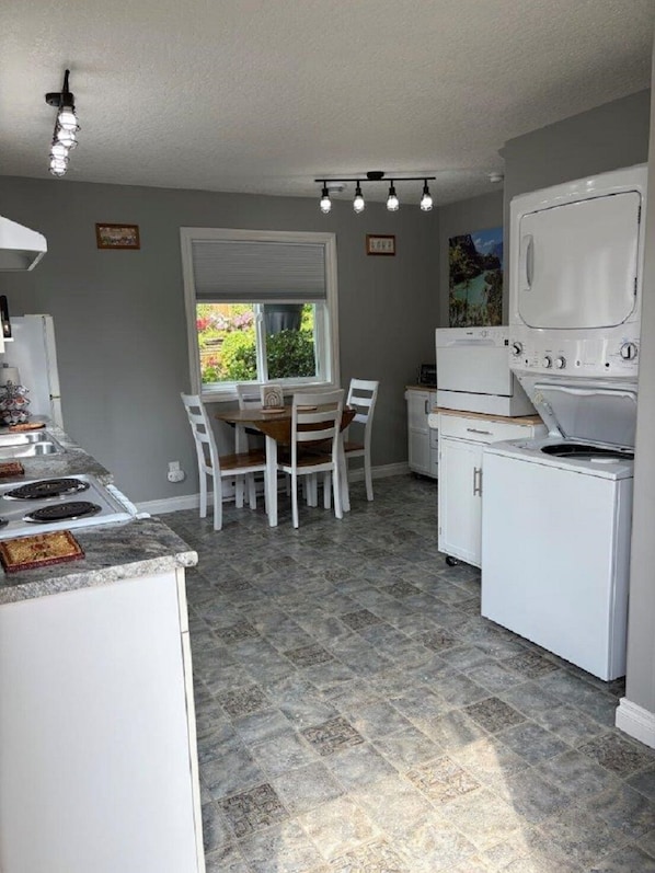 A kitchen with a dining table, chairs, a stove, and a refrigerator.