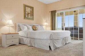 A bedroom with a bed, two bedside tables, a nightstand, a window with curtains, and a framed picture on the wall. - Perfect Central Branson Stay Golf Course View • Show Discounts (Branson)