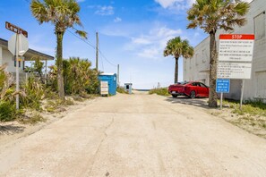 A road leading to a beach area with a stop sign, a red car parked on the side, and a blue portable toilet. - Beach Bungalow - Historic American Beach - 3 Bedrooms, 3 Bathrooms (Fernandina Beach)