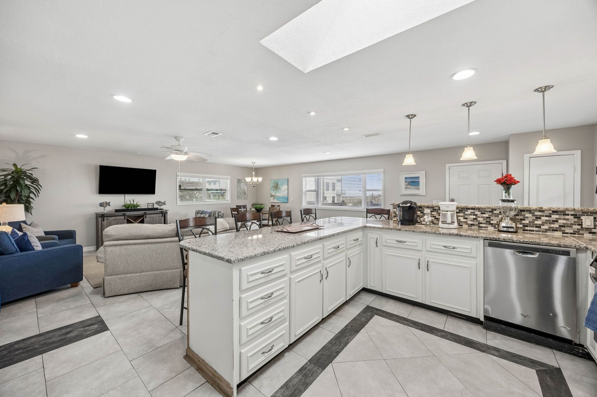 A modern kitchen with white cabinets, a granite countertop, and a dishwasher.