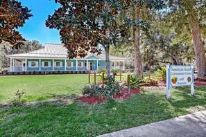 A building with a green and white facade, a covered porch, and a sign indicating it is the American Beach Community Center and Museum. - Beach Bungalow - Historic American Beach - 3 Bedrooms, 3 Bathrooms (Fernandina Beach)