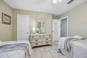 A bedroom with two beds, a dresser, a mirror, and a door. - Beach Bungalow - Historic American Beach - 3 Bedrooms, 3 Bathrooms (Fernandina Beach)