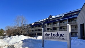 Ett snötäckt område med en skylt som visar vägen till hotellkomplexet ”The Lodge Condominium Hotel”.