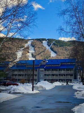 Un hôtel avec un toit bleu, une piste de ski en arrière-plan et un sol recouvert de neige.