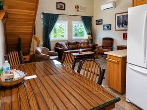 Ein gemütliches Zimmer mit einem Holztisch, Stühlen, einer Couch und einer Küchenzeile.