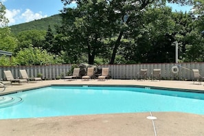 A swimming pool with lounge chairs and a wooden fence. - Loft Condo Sleeps 6 - Private Queen Bedroom, Indoor Pool & Hot Tub, Loon (Lincoln)