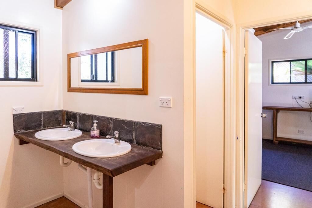 A bathroom with two sinks, a mirror, and a door leading to another room.