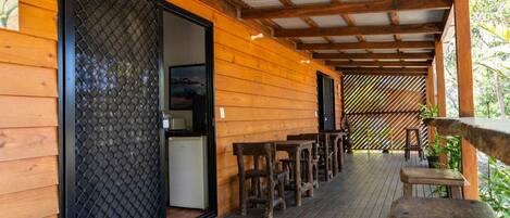 A wooden deck with outdoor seating, a sliding glass door, and a covered area with a metal roof.