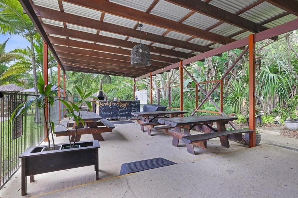 Un patio al aire libre con mesas de picnic, una lámpara colgante y un menú en una pizarra.