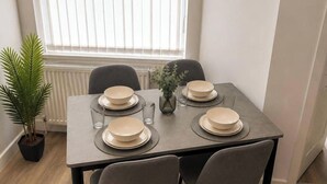 A dining table set with plates, glasses, and a vase. - Manchester Oasis - Spacious 4 Bedroom House (Manchester)