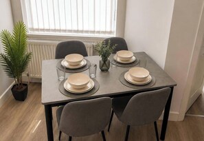 A dining table set with plates, glasses, and a vase. - Manchester Oasis - Spacious 4 Bedroom House (Manchester)