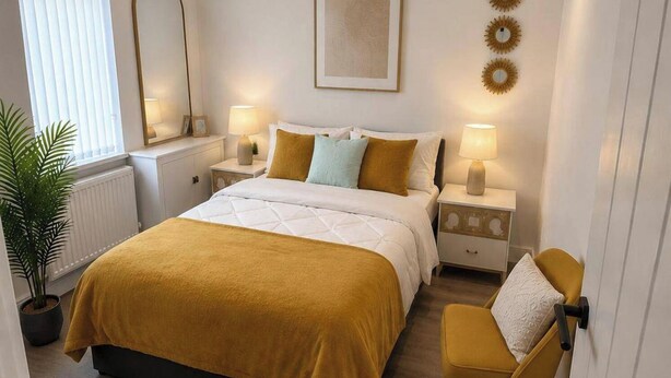 A hotel room with a bed, bedside tables, a chair, a potted plant, and a window with blinds. - Manchester Oasis - Spacious 4 Bedroom House (Manchester)