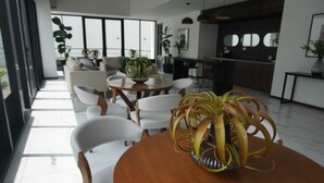 Um interior moderno com uma mesa de madeira redonda, cadeiras brancas e um vaso de planta.