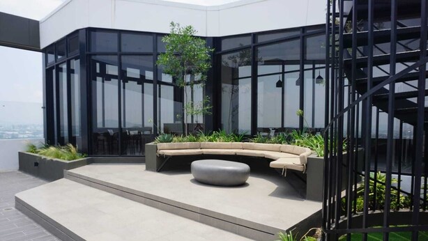 Um terraço no telhado com uma área de estar em curva, uma pequena mesa e uma escadaria.