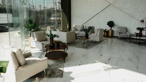 Uma sala de estar moderna com parede de vidro, sofás brancos, mesa de centro e plantas em vasos.