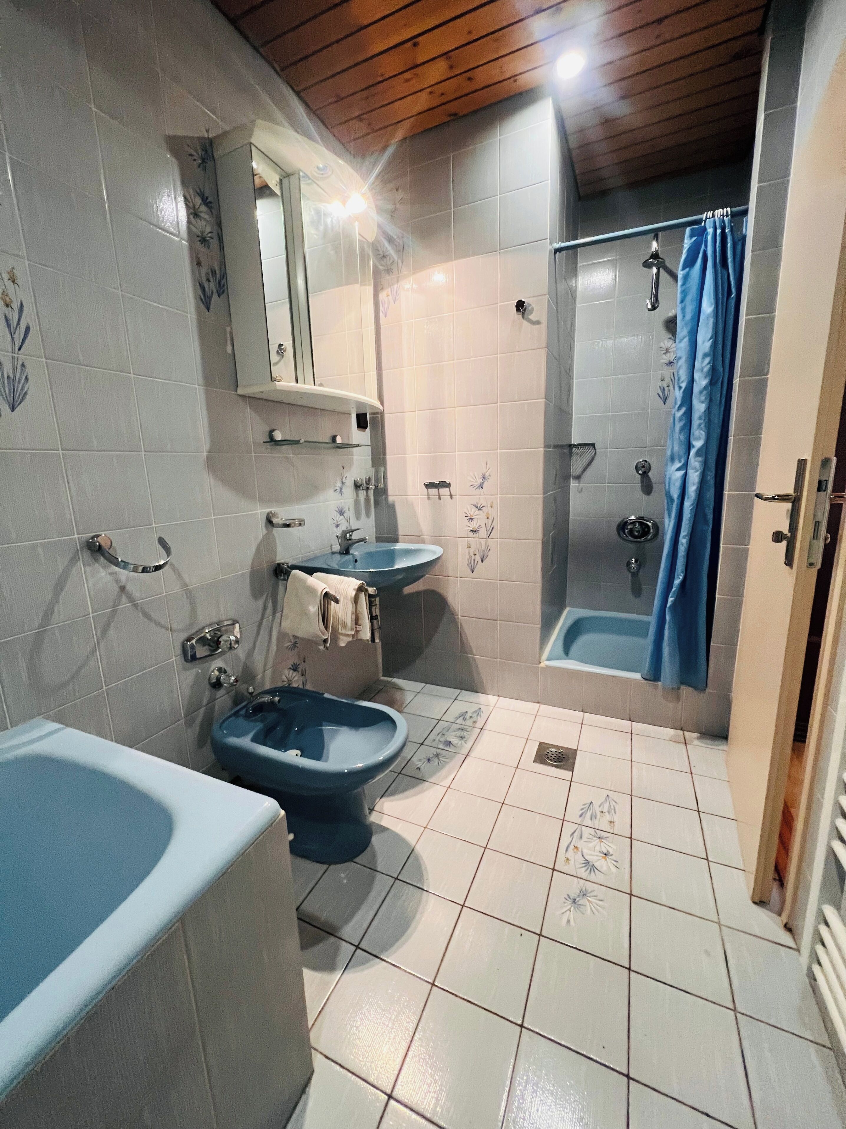 Et badeværelse med badekar, to håndvaske, toilet, bruseniche og et spejl.