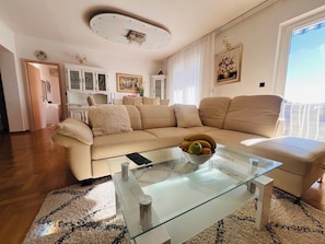 A living room with a beige sofa, a glass coffee table with a bowl of fruit, and a white cabinet in the background. - A6 - Spacious apt w pool, terrace and sea view (Dugi Rat)