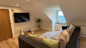 Un dormitori tipus loft modern amb un llit gran, un televisor penjat a la paret i un fanal.