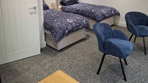 Une chambre avec deux lits, un bureau et deux chaises.