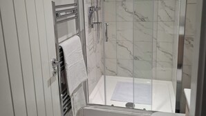 Une salle de bain moderne avec une douche à parois de verre, des toilettes blanches et un porte-serviettes.