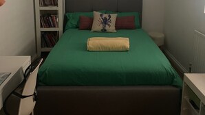 Een slaapkamer met een bed, een boekenkast, een bureau en een radiator.