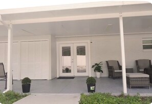 A covered porch with a sliding glass door, outdoor seating, and potted plants. - Spacious 3-Bedrooms. Home in Tampa. Fast WiFi & Free Parking (Tampa)