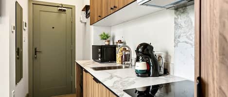 A compact kitchen with a built-in stove, a coffee maker, and a sink.