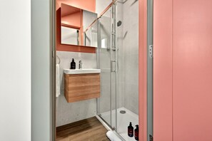 A modern bathroom with a glass shower enclosure, a wooden vanity, and a white sink. - GuestReady - Studio w Kitchenette in Harrow (London)