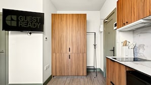 A modern kitchen with wooden cabinets, a built-in oven, and a 'GUEST READY' sign. - GuestReady - Trendy Studio in Harrow (London)