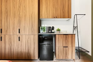 Eine kompakte Küche mit Holzausstattung, einem integrierten Geschirrspüler, einer Kaffeemaschine und einem kleinen Fenster.