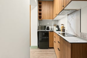 Eine moderne Küche mit Holzschränken, einem schwarzen Kühlschrank, einer Mikrowelle und einer Kaffeemaschine.