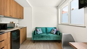 A compact kitchen with wooden cabinets, a microwave, and a dishwasher. - GuestReady - Large Studio w Kitchen in Harrow (London)