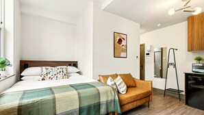 A modern room with a bed, a sofa, a small kitchen area, and a bathroom visible through an open door. - GuestReady - Contemporary King Studio in Harrow (London)