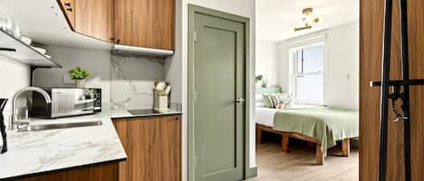 A compact kitchen with wooden cabinets, a built-in microwave, and a small countertop.