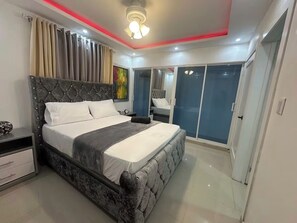 A modern bedroom with a large bed, a nightstand, a dresser, and a wardrobe. - 20 minutes from the airport, Torres Catalana is ideal for families (Santo Domingo Este)