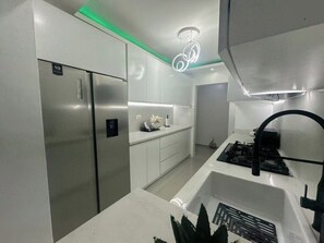 A modern kitchen with stainless steel appliances, white cabinetry, and a gas stove. - 20 minutes from the airport, Torres Catalana is ideal for families (Santo Domingo Este)
