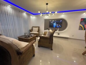 A living room with wicker furniture, a flat-screen TV, and a ceiling light fixture. - 20 minutes from the airport, Torres Catalana is ideal for families (Santo Domingo Este)