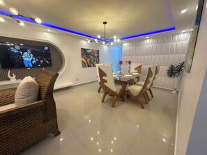 A modern living room with a television, dining table, and chairs. - 20 minutes from the airport, Torres Catalana is ideal for families (Santo Domingo Este)