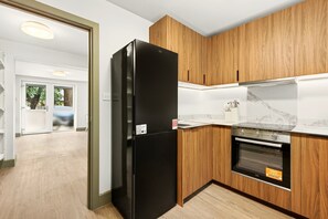 A modern kitchen with wooden cabinets, a black refrigerator, and a built-in oven. - GuestReady - Modern 1BR w Full Kitchen in Harrow (London)