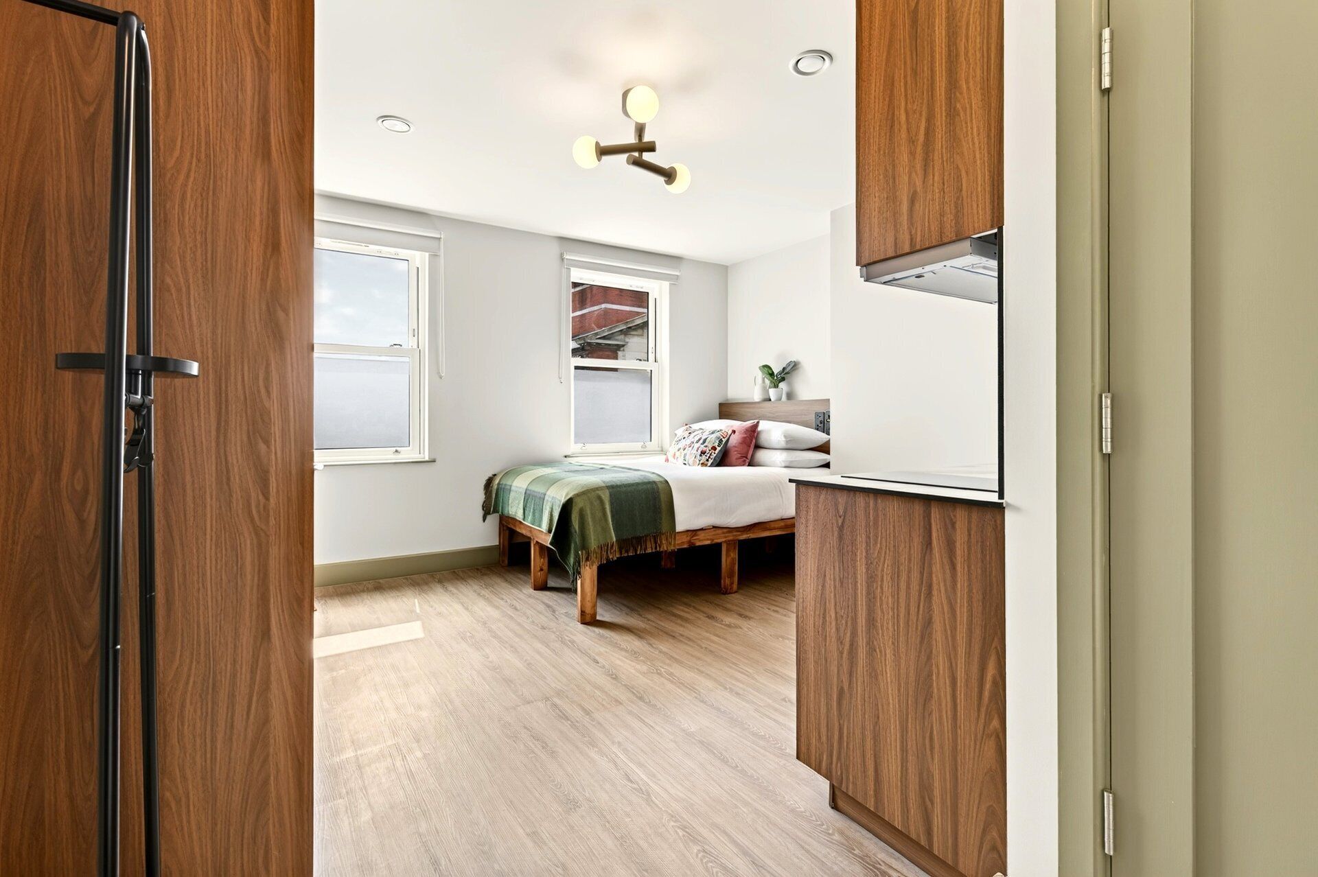 A bedroom with a bed, a bedside table, a window, and a ceiling light fixture.