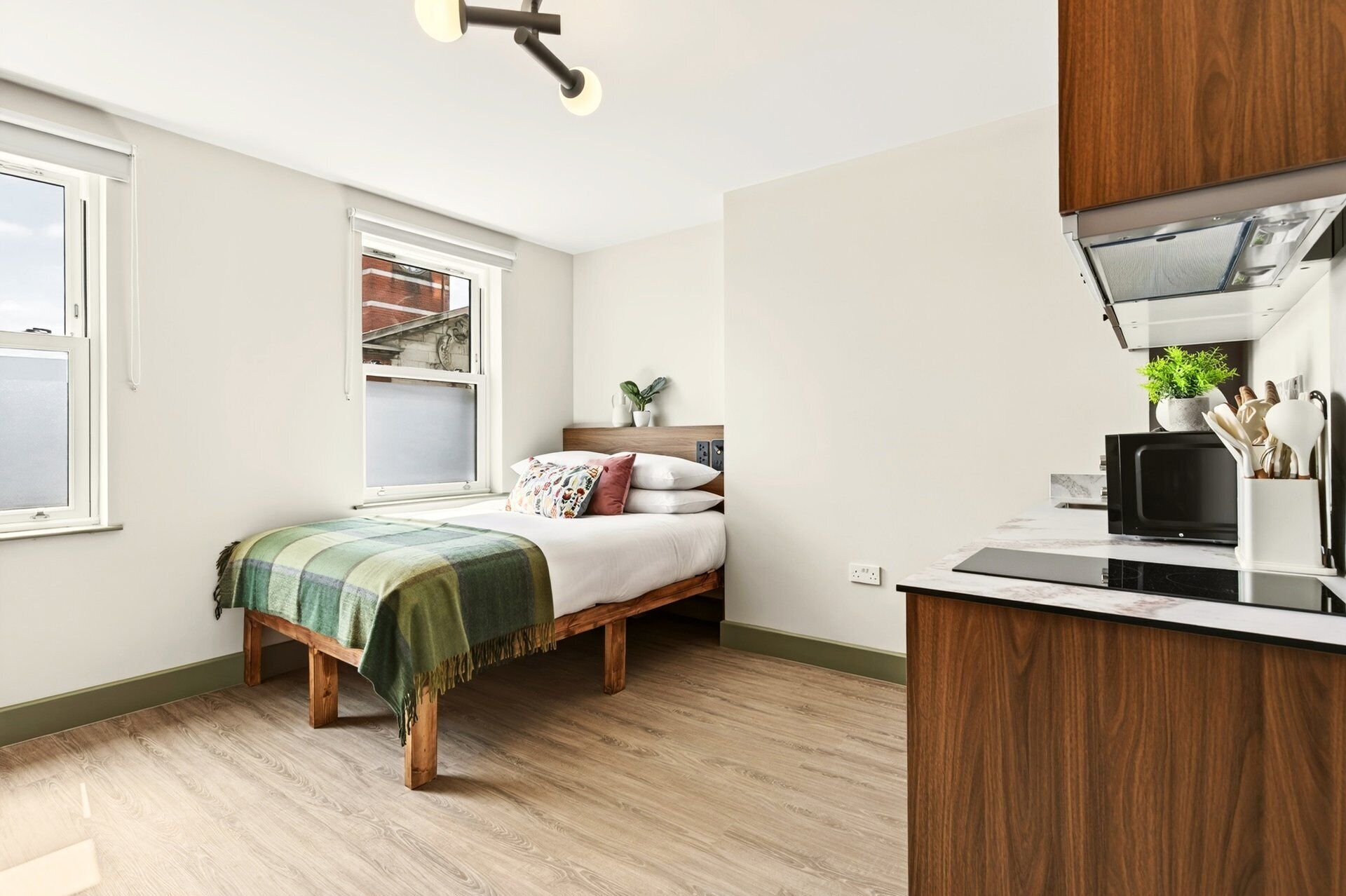 A compact bedroom with a bed, a window, and a kitchenette area with a microwave.