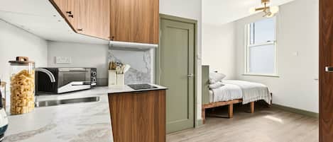 A compact kitchen with wooden cabinets, a microwave, and a marble countertop.