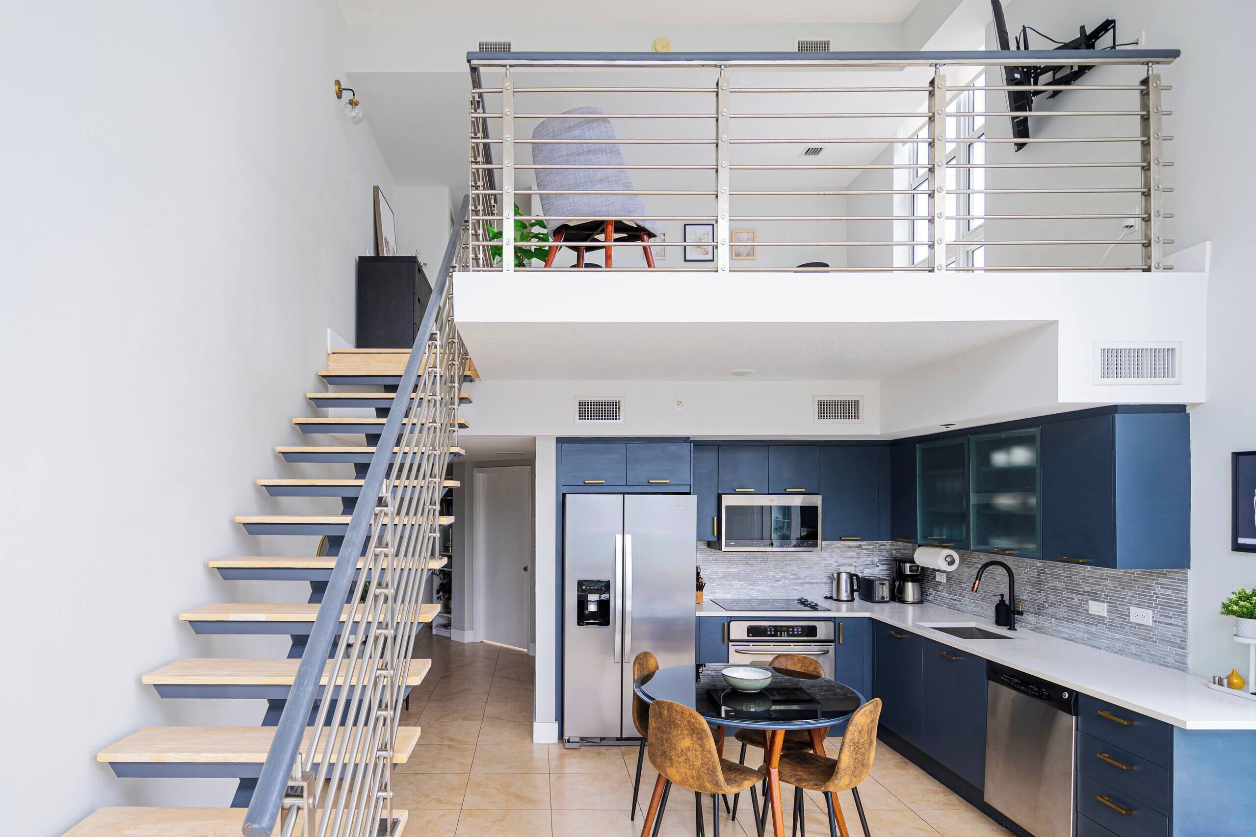 Eine moderne Küche mit Essbereich, einer Treppe und einem Balkon.