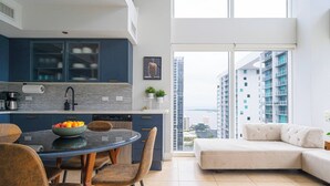 Une cuisine moderne avec un coin repas, un canapé et une vue sur les immeubles de grande hauteur.
