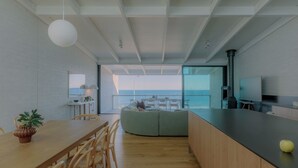 Een moderne keuken met een eethoek, een groot raam met uitzicht op zee, en een inbouwfornuis.