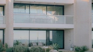 Een modern gebouw met twee verdiepingen, grote ramen, een balkon en een aangelegde tuin.