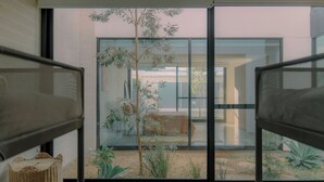 Een moderne kamer met een grote glazen deur naar een buitenruimte met planten en een zithoek.