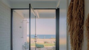 Een gang met een glazen deur die uitkomt op een balkon met uitzicht op het strand.