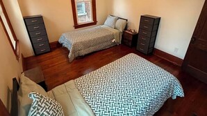 Un dormitorio con dos camas, un ventilador de techo, una ventana y dos cómodas.